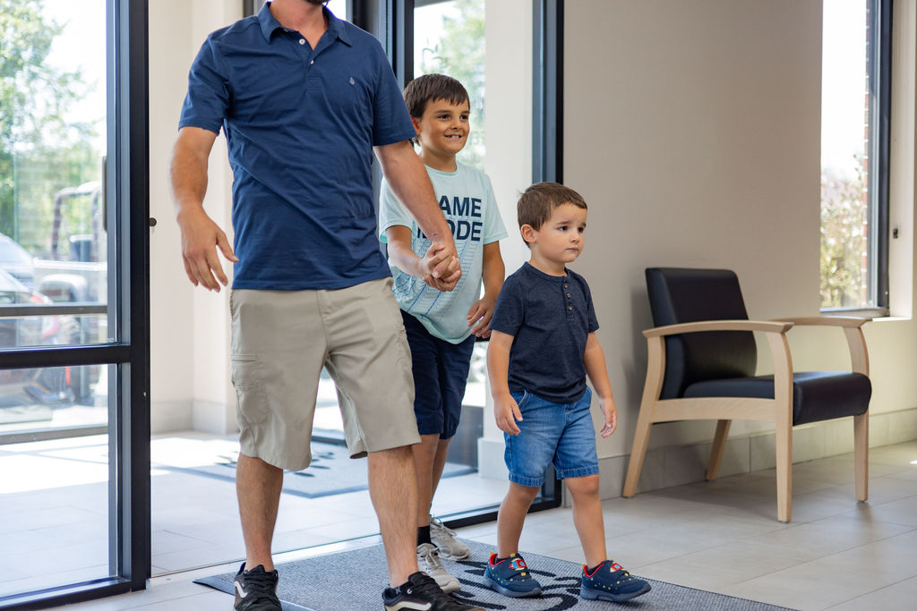 A Dad and two children Walking into the Pediatric Dentist at Virginia Family Dentistry